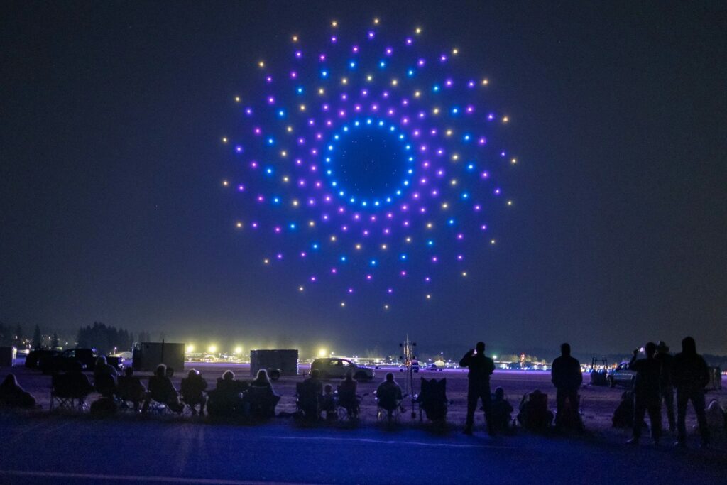 Mandala violet de drones lumineux devant des spectateurs