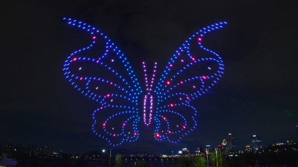 Papillon bleu géant en drones lumineux au-dessus d'une ville