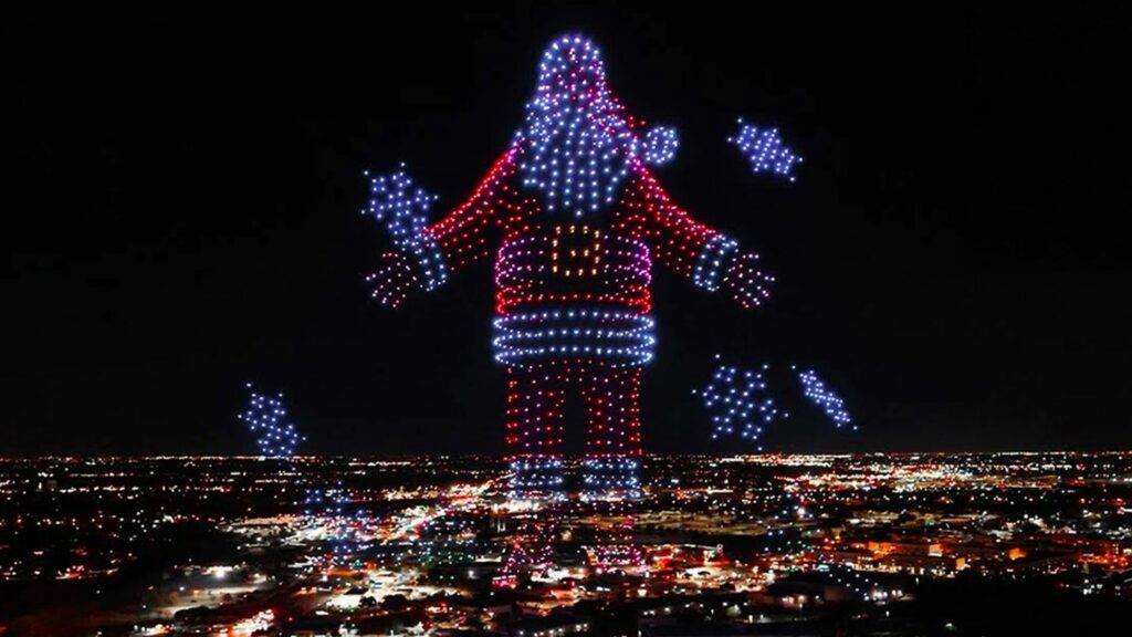 Père Noël géant en drones lumineux au-dessus d'une ville